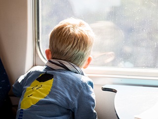 Un petit garçon regarde à travers la fenêtre du train