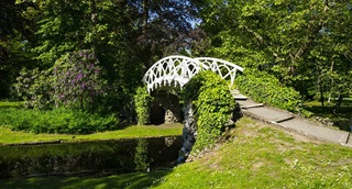 Een witte gesmede metalen brug in het park.