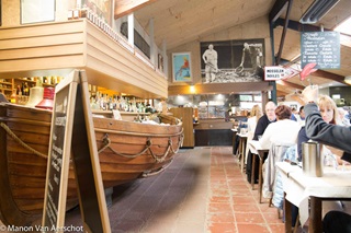 Intérieur du restaurant spécialisé dans les produits de la mer De Oesterput avec un bar en forme de bateau.